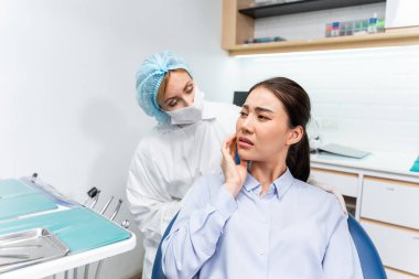 Beyaz dişçi diş sağlığı kliniğindeki genç kız için dişleri muayene ediyor. Çekici kadın hasta, dişçi koltuğuna oturur, hastanede muayene sırasında doktordan diş tedavisi görür..