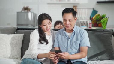 Çift birlikte oturup mutlu bir şekilde akıllı telefon kullanıyor.