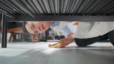 Mobilyaların altını bezle temizleyen kişi