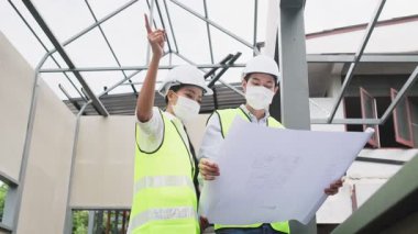 Asyalı işçiler, covid salgın krizi nedeniyle mimari alanında koruyucu yüz maskesi takıyorlar.