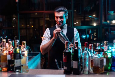 Kafkas barmeni bir barda müşteriye kokteyl hazırlıyor. Çekici barmen likör karışımını karıştırıyor. Kokteyl karıştırıcısından, gece kulübü restoranının bardağına..