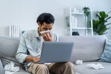 Asyalı yakışıklı erkek, oturma odasında çalışırken burnunu kaçırıyor. Çekici genç adam koltukta oturup kötü hissediyor ve alerji yüzünden acı çekiyor. Sonra da evde hapşırırken burnunu peçete ile örtüyor..