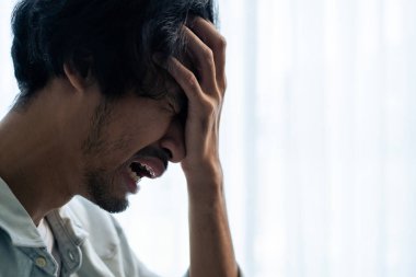 Asyalı genç üzgün bir adam evde tek başına oturuyor. Çekici mutsuz erkek çok üzgün, yalnız ve hayal kırıklığına uğramış para borçlarını, bütçe kayıplarını, iflasları düşünün..