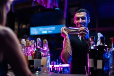 Kafkas barmeni bir barda müşteriye kokteyl hazırlıyor. Çekici barmen likör karışımını karıştırıyor. Kokteyl karıştırıcısından, gece kulübü restoranının bardağına..