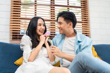 Asyalı genç adam sürpriz yaptı ve gül çiçeğini güzel kız arkadaşına verdi. Çekici, romantik, yeni evli çift erkek ve kadın yıl dönümünü ve Sevgililer Günü 'nü kutlamak için birlikte evde vakit geçirirler..