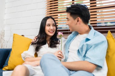 Asyalı genç adam sürpriz yaptı ve gül çiçeğini güzel kız arkadaşına verdi. Çekici, romantik, yeni evli çift erkek ve kadın yıl dönümünü ve Sevgililer Günü 'nü kutlamak için birlikte evde vakit geçirirler..