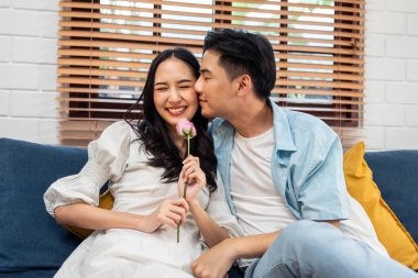 Asyalı genç adam sürpriz yaptı ve gül çiçeğini güzel kız arkadaşına verdi. Çekici, romantik, yeni evli çift erkek ve kadın yıl dönümünü ve Sevgililer Günü 'nü kutlamak için birlikte evde vakit geçirirler..