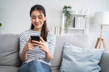 Asyalı güzel bir kadın kanepede oturuyor ve evdeki cep telefonunu çalıyor. Mutlu çekici genç kız evde vakit geçirir, rahatlar, iletişim kurar ve oturma odasında akıllı telefondan tartışır.