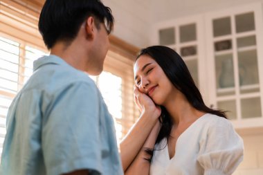 Asyalı genç adam ve kadın evdeki oturma odasında birbirlerine bakıyorlar. Çekici, romantik, yeni evli çift erkek ve kadın birlikte vakit geçiriyorlar. Yıldönümünü ve sevgililer gününü evde kutluyorlar..