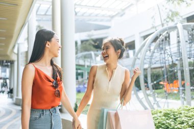 Asyalı genç iki kadın açık hava mağazasında alışveriş yapıyor. Alışveriş torbaları tutan güzel bir kadın. Mutlulukla tek başına yürüyor. Alışveriş merkezinden veya mağazadan alışveriş yapmaktan hoşlanıyor..