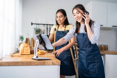 Asyalı bacak ampüte kadın fırın evde mutfakta satmak için. Önlük takan, koltuk değneği kullanan, mutlu ve heyecanlı, çekici bir kadın..