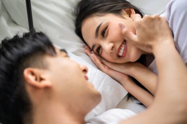 Asyalı yeni evli çift yatağa uzanıp birbirlerine bakıyorlar. Pijamalı çekici genç adam ve kadın evdeki yatak odasında sabahın erken saatlerinde eğleniyorlar. Aile ilişkisi kavramı