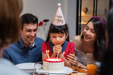 Çok ırklı büyük bir aile, küçük kız çocukları için doğum günü partisi veriyor. Çok hoş bir çeşitlilik anı. İnsanlar küçük kız çocuğuna doğum günü şarkısı söylüyor. Sonra da yemek masasında pastaya mum üflüyor.