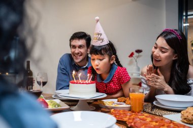 Çok ırklı büyük bir aile, küçük kız çocukları için doğum günü partisi veriyor. Çok hoş bir çeşitlilik anı. İnsanlar küçük kız çocuğuna doğum günü şarkısı söylüyor. Sonra da yemek masasında pastaya mum üflüyor.