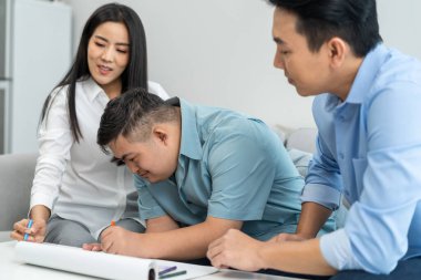 Asyalı mutlu aile, evdeki oturma odasında oğluyla resim çiziyor. Güzel, sevgi dolu anne ve baba evde resim çizmeyi sabırlı bir gence öğretiyor. Yaşam tarzı etkinliği