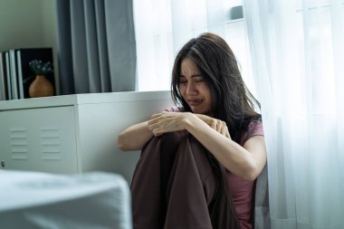 Asyalı genç üzgün kadın evde tek başına oturuyor. Çekici mutsuz kadın çok üzgün, yalnız ve hayal kırıklığına uğramış para borçlarını, bütçe kayıplarını, iflasları düşün.