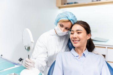 Beyaz dişçi diş sağlığı kliniğindeki genç kız için dişleri muayene ediyor. Diş hekimliği koltuğunda yatan çekici kadın hastanede muayene sırasında doktordan diş tedavisi görüyor.