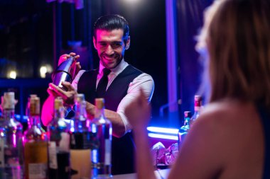 Kafkasyalı barmen bir barda kadınlara kokteyl hazırlıyor. Çekici barmen likör karışımını karıştırıyor. Kokteyl karıştırıcısından, gece kulübü restoranının bardağına..