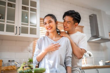 Asyalı romantik adam mutfakta kolyesiyle sürpriz sevgili yapıyor. Çekici, romantik, yeni evli çift erkek ve kadın birlikte vakit geçiriyorlar. Yıldönümünü ve sevgililer gününü evde kutluyorlar..