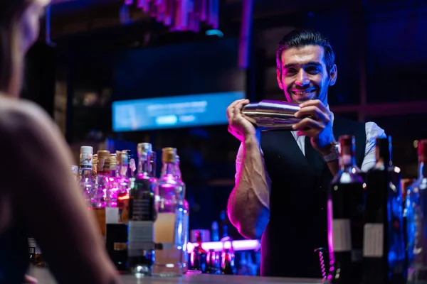 Kafkas barmeni bir barda müşteriye kokteyl hazırlıyor. Çekici barmen likör karışımını karıştırıyor. Kokteyl karıştırıcısından, gece kulübü restoranının bardağına..