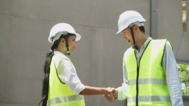 İki inşaat işçisi dışarıda el sıkışıyor.