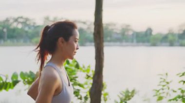 Asya 'lı genç ve güzel bir kadın, halk parkında gün batımında sağlık için koşuyor. Sporcu formda ve sıkı bir kız sağlıklı olması için dışarıda spor yaparak egzersiz yapıyor..