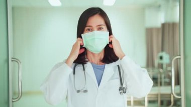 Maske takan kadın steteskopunu ayarlıyor.