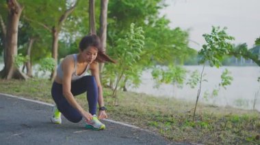 Mutlu Asyalı genç güzel bir kadın akşam vakti spor kıyafetler giyerek parktaki sokakta duruyor..