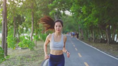 Asyalı genç ve güzel bir kadın akşam vakti sağlık için koşuyor. Sokakta, parkta..