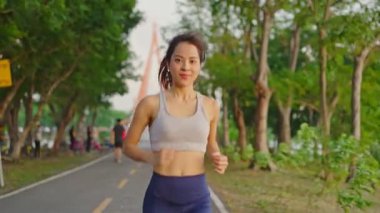 Asyalı genç ve güzel bir kadın akşam vakti sağlık için koşuyor. Sokakta, parkta..