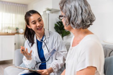 Asyalı bakıcı hemşire, Kafkasyalı yaşlı kadın hastayı evde muayene ediyor. Çekici uzman bakıcı kadınlar destek oluyor, yaşlı olgun büyükannelere danışmanlık yapıyor ve danışmanlık yapıyorlar..