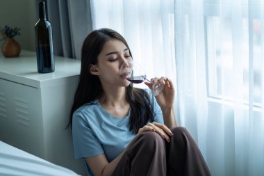 Asyalı genç bunalımlı kadın kalbi kırık ve şarap içiyor. Çekici güzel kız elinde bir şişe alkolle yerde oturuyor yalnızlık çekiyor, sarhoş ve akşamdan kalma halde oturma odasında tek başına..