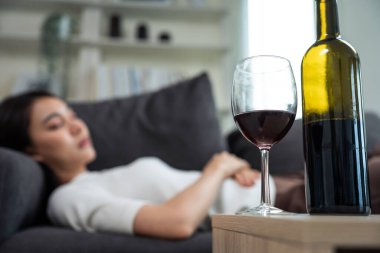 Asyalı genç bunalımlı kadın kalbi kırık ve alkol içiyor. Çekici güzel kız yalnızlık çekiyor, sarhoş ve akşamdan kalma, kanepeye uzanmış, oturma odasında bir kadeh şarap tutuyor..