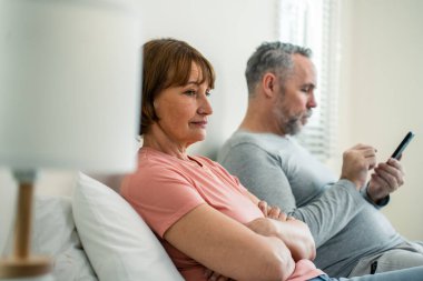 Telefon bağımlılığı, beyaz bir koca karısına dikkat etmez. Aile sorunları, yaşlı ve olgun bir çift yatakta oturuyor ve akıllı telefon kullanıyor. Yatak odasında birbirlerini görmezden geliyorlar..