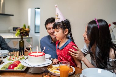 Çok ırklı büyük bir aile, küçük kız çocukları için doğum günü partisi veriyor. Çok hoş bir çeşitlilik anı. İnsanlar küçük kız çocuğuna doğum günü şarkısı söylüyor. Sonra da yemek masasında pastaya mum üflüyor.