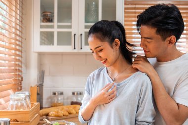 Asyalı romantik adam mutfakta kolyesiyle sürpriz sevgili yapıyor. Çekici, romantik, yeni evli çift erkek ve kadın birlikte vakit geçiriyorlar. Yıldönümünü ve sevgililer gününü evde kutluyorlar..