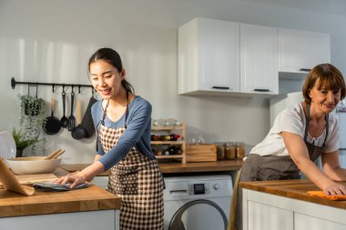 Beyaz, yaşlı, yaşlı bir kadın kızıyla birlikte mutfağı temizliyor. Çekici kadın hizmetçi ve olgun temizlikçi önlük giyer, ev işleri ya da ev işleri için çalışırken mutlu olur ve rahatlar..