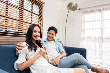 Asyalı genç adam sürpriz yaptı ve gül çiçeğini güzel kız arkadaşına verdi. Çekici, romantik, yeni evli çift erkek ve kadın yıl dönümünü ve Sevgililer Günü 'nü kutlamak için birlikte evde vakit geçirirler..