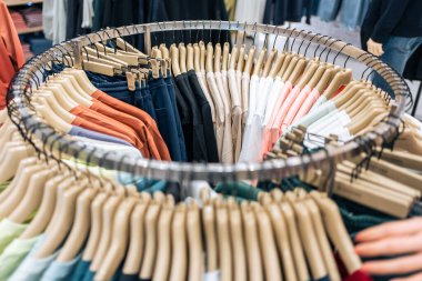 Asyalı genç kadınların yakından bakınca alışveriş merkezindeki kıyafetlerin ürünü gibi görünüyorlar. Çekici, mutlu bir kız alışveriş merkezinde yeni elbise ve giysi raflarından yeni tişört seçmek için mağazaya girmekten hoşlanır..