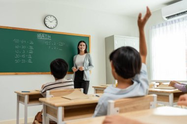 Bir grup öğrenci ilkokulda sınıfta öğretmenle birlikte öğreniyor. Çekici, güzel bayan eğitmen. Anaokulunda küçük çocukları mutluluk ve eğlence ile eğitmek ve eğitmek..