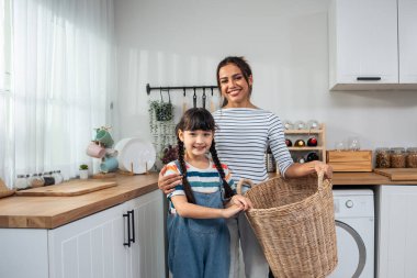 Kirli çamaşırları yıkamayı öğreten beyaz bir annenin portresi. Genç kız anne babasından evde temizlik için çamaşır makinesine çamaşır koymayı öğreniyor. Ev Hizmetleri..