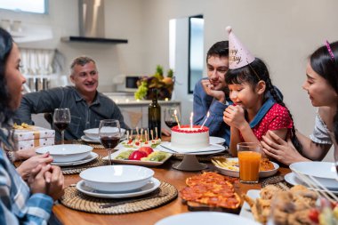 Çok ırklı büyük bir aile, küçük kız çocukları için doğum günü partisi veriyor. Çok hoş bir çeşitlilik anı. İnsanlar küçük kız çocuğuna doğum günü şarkısı söylüyor. Sonra da yemek masasında pastaya mum üflüyor.