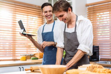 Asyalı genç LGBTQ erkek eşcinsel ailesi evde mutfakta fırın yapmayı seviyor. Çekici, romantik erkek çift önlük giyer. Evde birlikte yemek pişirmek için mutlu ve neşeli olurlar..