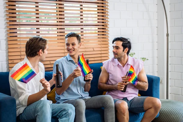 Beyaz, yakışıklı, gay bir aile, LGBTQ bayrağı taşıyor ve birlikte dans ediyorlar. Çekici genç erkek lgbt çifti müzik dinleyerek ve eğlenerek, neşeli gururla eğlenerek ve gökkuşağı bayrağı taşıyarak vakit geçirir.