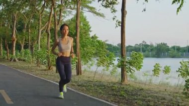 Asyalı genç ve güzel bir kadın akşam vakti sağlık için koşuyor. Sokakta, parkta..