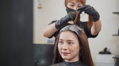 Kuaför güzellik salonunda kadına saç boyası yapıyor.