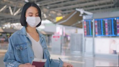 Coronavirüs enfeksiyonunu önlemek için COVID salgını sırasında havaalanı terminalinde yürüyen yüz maskesi takan kadın yolcu.. 