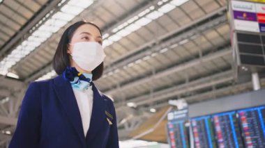 Uçuş terminalinde yüz koruyucu maske takan kadın.