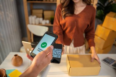 Cep telefonuyla mal için ödeme yapan müşterilerin ellerini kapatın. Yakışıklı erkek müşteri depodaki küçük işletmelerden gelen ürünlere kolay ve kolay bir ödeme yapıyor.