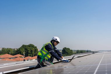 Profesyonel mühendis fotovoltaik panel sisteminin bakımı için çalışıyor. Çatı teftişi yapan çekici teknisyen güneş pili ekipman kutusunu gün batımında güneş pili alanında inceleyip kontrol ediyor.